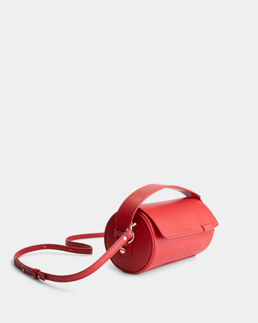 Luxury handbag and crossbody bag in red with a unique cylindrical silhouette, handmade from vegan, sustainable, and cruelty-free Kayla Fabric™—an eco-friendly leather alternative. Designed by a Dutch designer, this authentic bag is lightweight, featuring a magnetic flap and soft gold hardware for a touch of elegance. The best designer handbag for those seeking ethical style and versatility in an everyday accessory. Made in Europe.