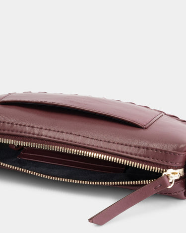 Luxury mini shoulder bag in burgundy, handcrafted in collaboration with AVDW Antwerp from vegan, sustainable, and cruelty-free Kayla Fabric™—an eco-friendly leather alternative. Designed by a Dutch designer, this authentic bag features a compact, curved design with hand-knotted cords and soft gold accents, blending artistry with practicality. The best designer handbag for those seeking ethical elegance. Made in Europe.