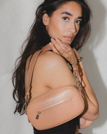 Brunette model holding Poppy Sandy Brown shoulder Bag made from environmentally conscious material Kayla Fabric